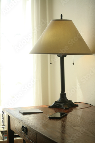 A cell phone, a lamp and a memo pad on a desk