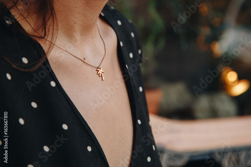 fashion details. woman wearing a black and white polka dot off dress. wearing a small and trendy gold palm tree necklace. ideal summer outfit accessories. european fashion blogger streetstyle.