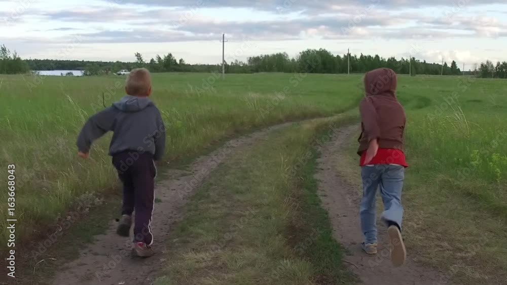 Two kids running together on rural road, slow motion Two kids running together on rural road, slow motion