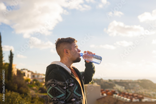 Portrait of a man drinking water from a bottle outside