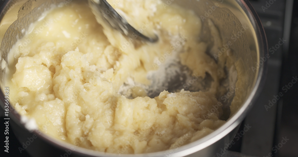 Handheld shot of mixing flour with butter mix for making choux dough Handheld shot of mixing flour with butter mix for making choux dough