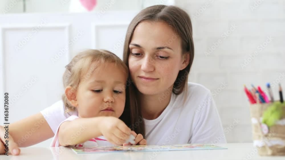 Mother and daughter doing a puzzle together in the light living room Mother and daughter doing a puzzle together in the light living room