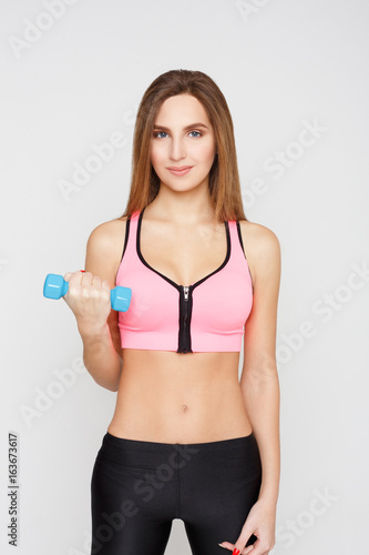 Fitness model woman with dumbbells on white