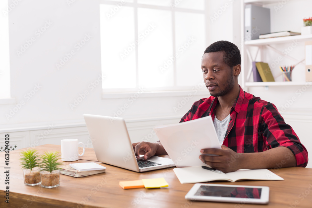 Black businessman in casual office, work with laptop and documents Black businessman in casual office, work with laptop and documents