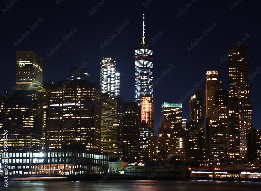 The Freedom Tower, Wall Street, and the skyline of downtown Manhattan from Brooklyn at sunset. 