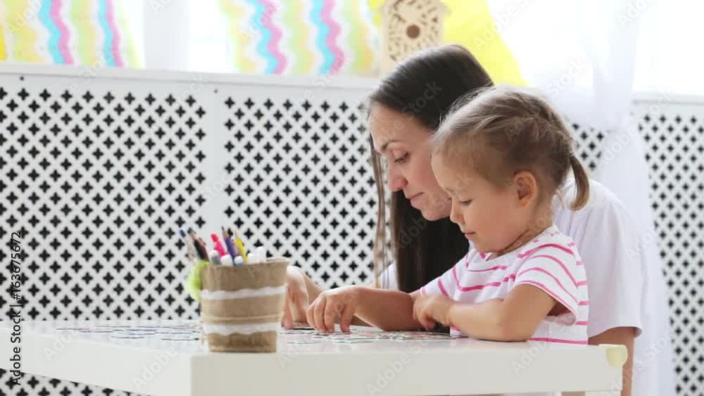 Mother and daughter doing a puzzle together in the light living room Mother and daughter doing a puzzle together in the light living room