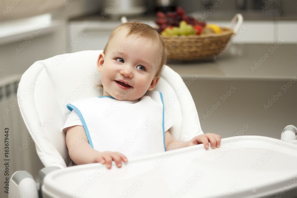 Little boy sitting in a high chair and laughing Little boy sitting in a high chair and laughing