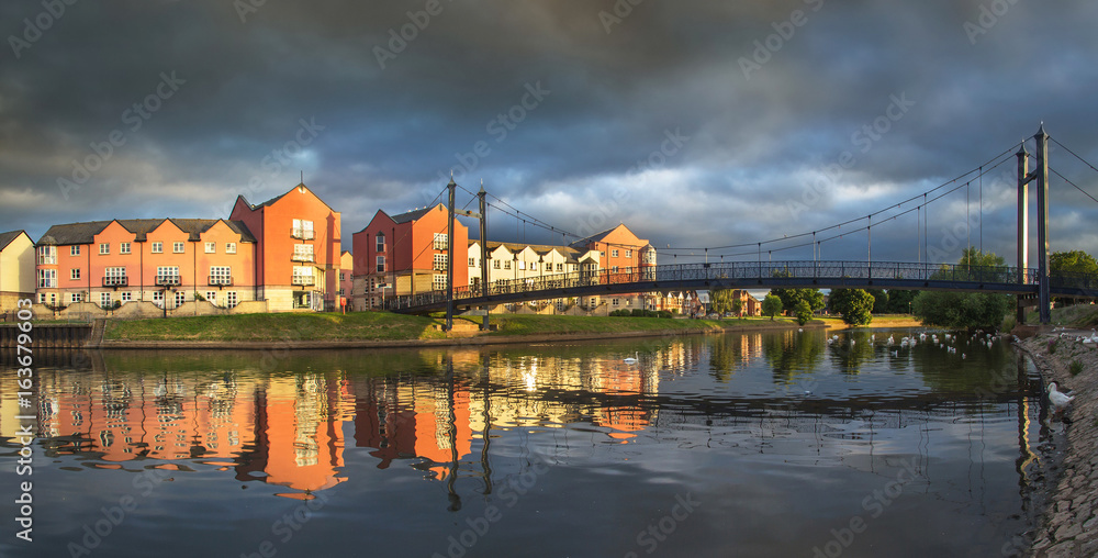 Houses on the waterfront in the city of Exeter. Sunset with a dramatic stormy sky. Devon. UK