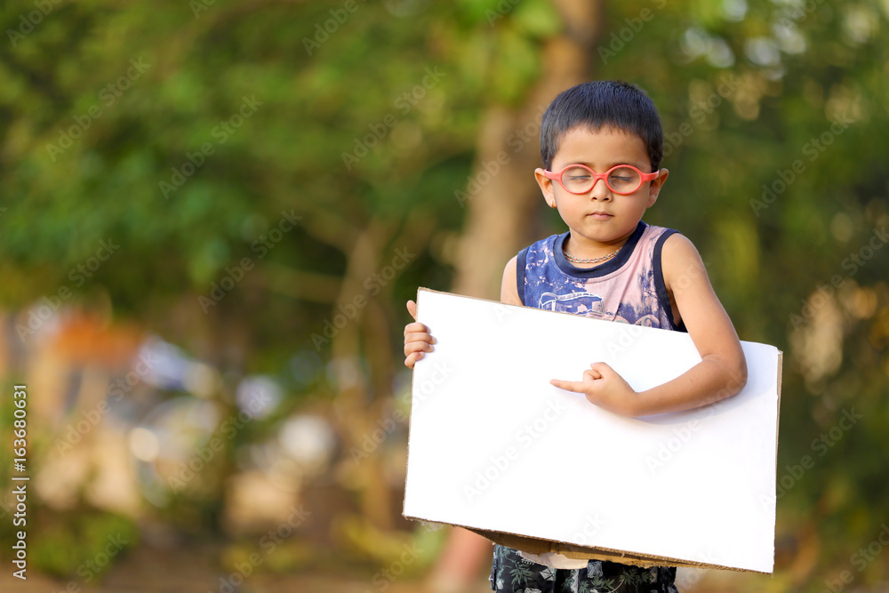 Indian child on eyeglass holding white board in hand Indian child on eyeglass holding white board in hand