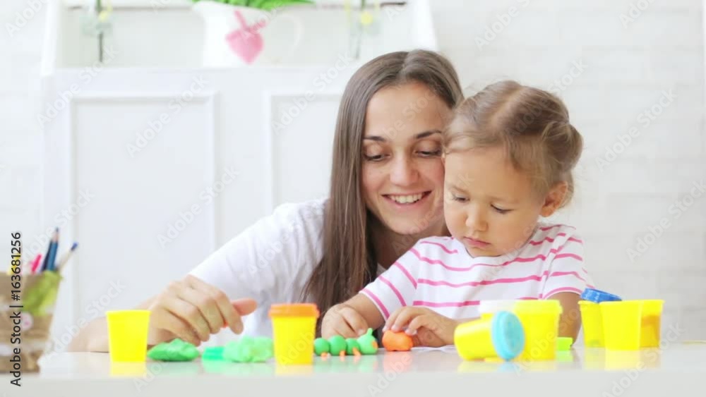 Young attractive mother with little cute daughter play with modeling clay Young attractive mother with little cute daughter play with modeling clay