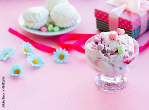 berry ice cream in glass dessert bowl on blurred background with gifts, sweets, pink background, selective focus, blur