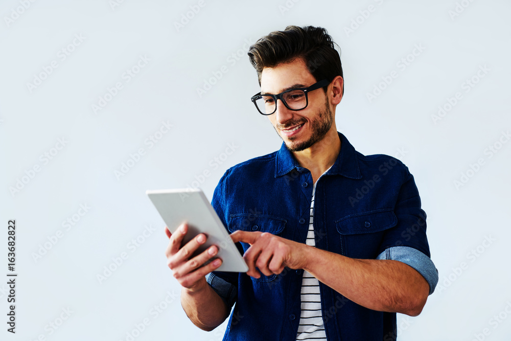 Young casually dressed man browsing on tablet Young casually dressed man browsing on tablet