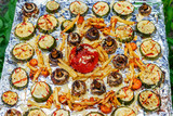 Tray with fried vegetables prepared on the grill on the foil . On a background of green grass.