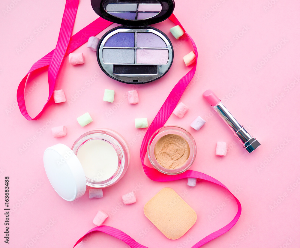 Fototapeta premium Fashion concept : Flat lay of pink cute woman bag lipstick, creams, honey, marshmallow, powder on colorful background with copy space