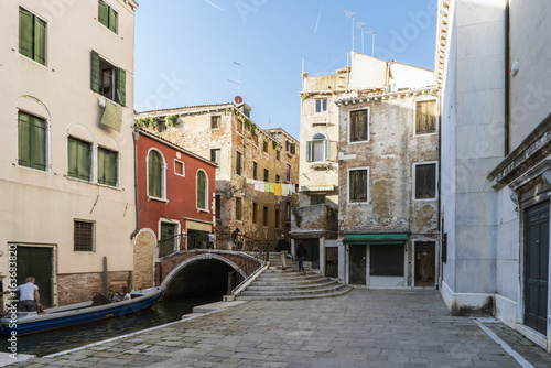  Tourists in the Plaza called "Campo de San Cassiano" with a bridge over a narrow canal and with clothes lying across it in Venice, Italy