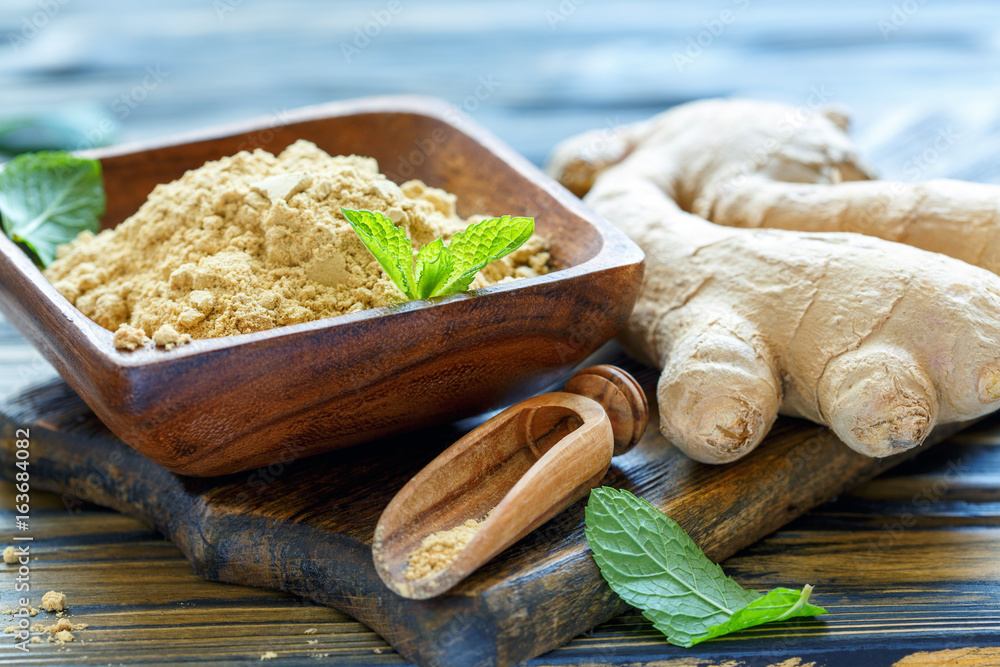 Ground ginger in a wooden bowl and ginger root. Ground ginger in a wooden bowl and ginger root.