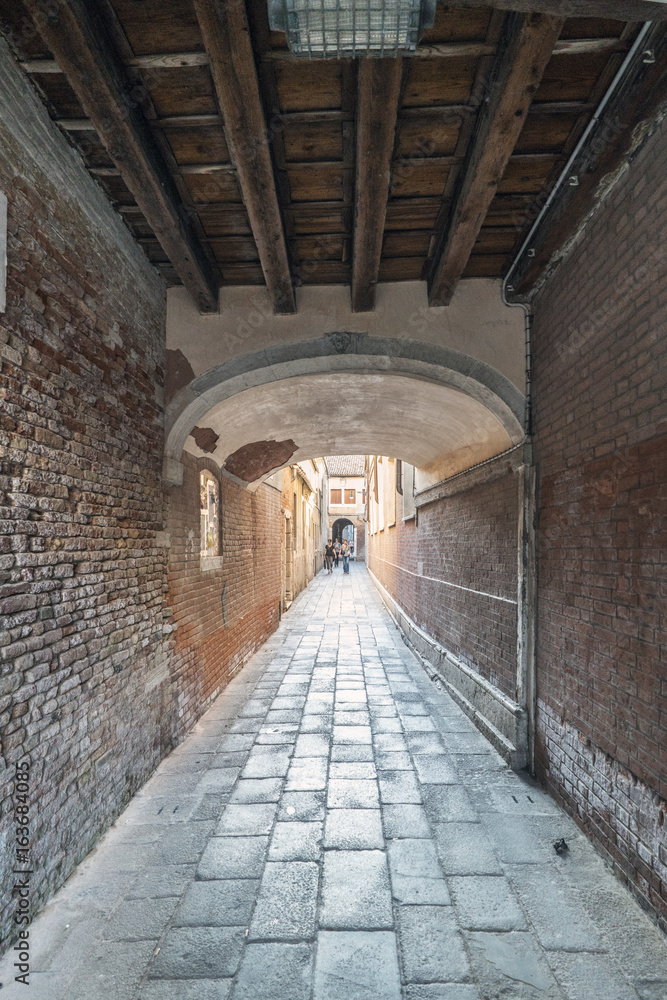 Tunnel and narrow alley of cobblestones in the oldest part of Venice, Italy