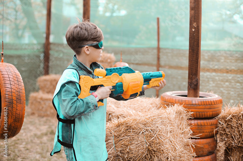 Foto Young boy with blaster attack and play with friends in protective glasses