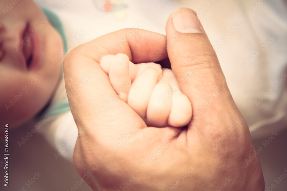 Parent holding his newborn baby hand symbolizing love and care Parent holding his newborn baby hand symbolizing love and care