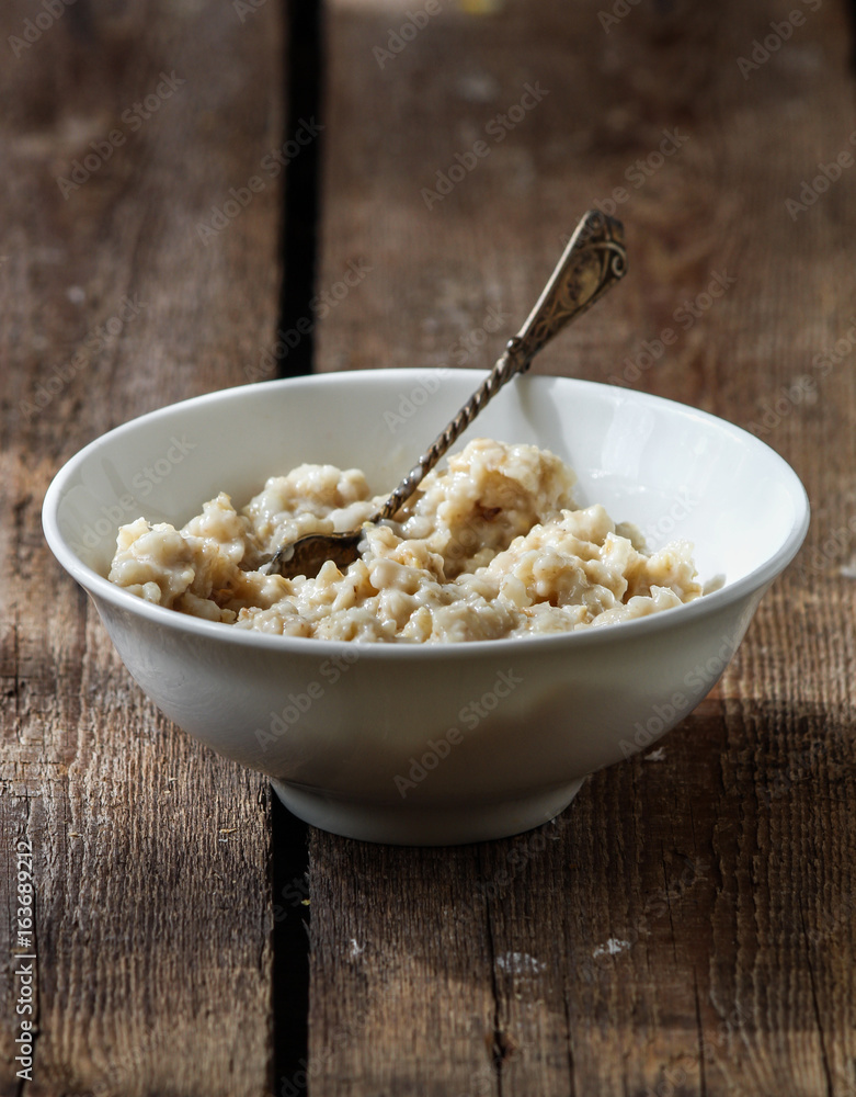 Ready-made, hot oatmeal in a white plate with a spoon Ready-made, hot oatmeal in a white plate with a spoon