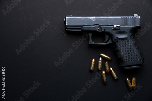 Murais de parede Gun with ammunition on dark table background.