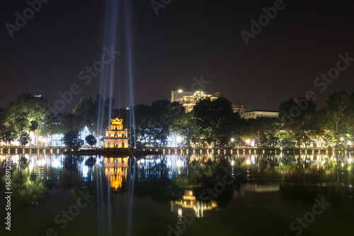 Night view of the Hoan Kiem Lake  Lake of the Returned Sword  and the Turtle Tower among blue light rays at historic centre of Hanoi in Vietnam. The Hoan Kiem Lake is a popular tourist destination.