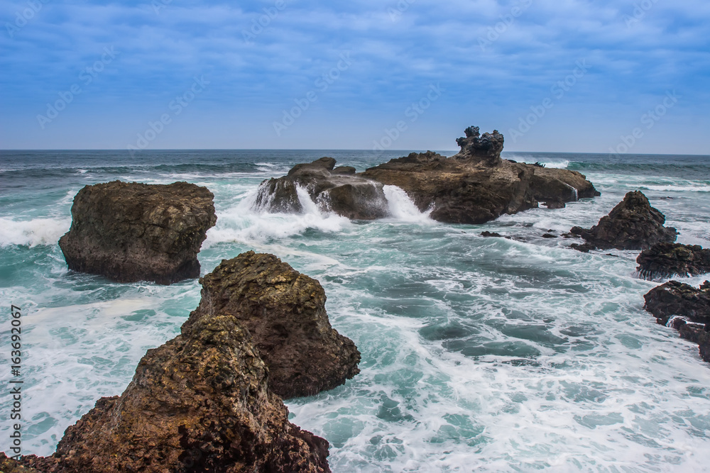 Cliffs in the ocean. Waves breaking on the rocks. Pacific Ocean.