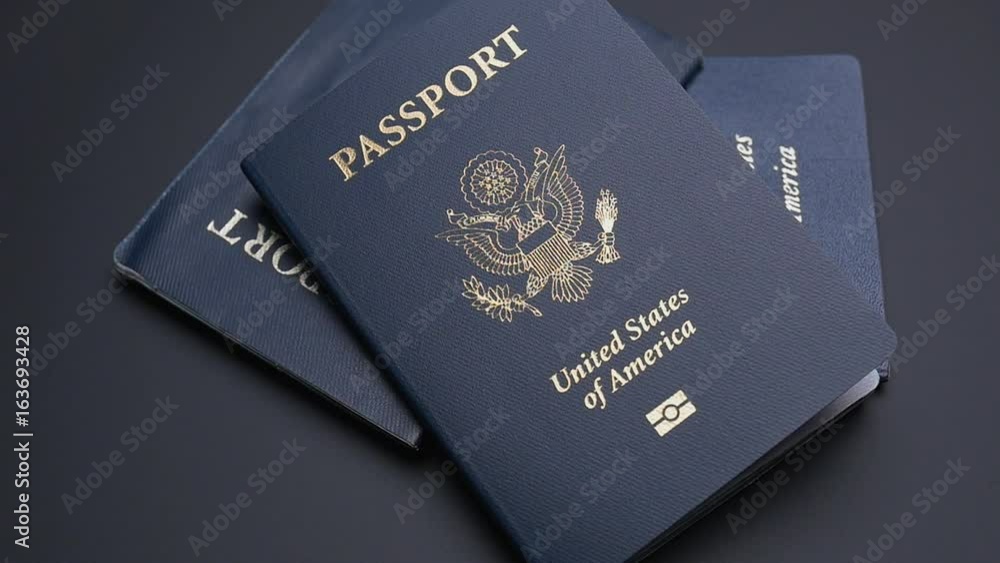 THREE AMERICAN PASSPORTS DROP INTO FRAME IN SLOW MOTION THREE AMERICAN PASSPORTS DROP INTO FRAME IN SLOW MOTION