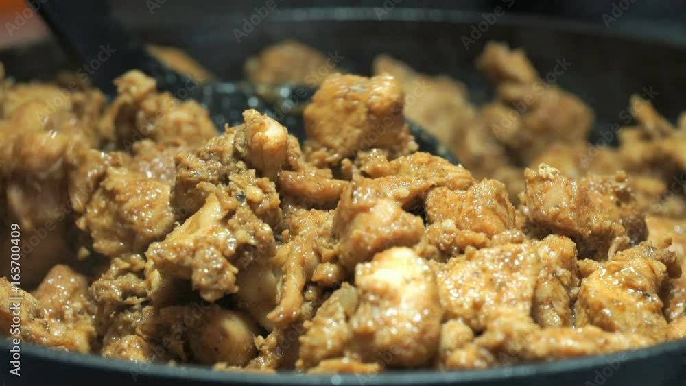 The black plastic spoon mixes fried slices during frying. The process of frying the chopped chicken pieces for cooking kebabs on the cast iron skillet. Close-up The black plastic spoon mixes fried slices during frying. The process of frying the chopped chicken pieces for cooking kebabs on the cast iron skillet. Close-up