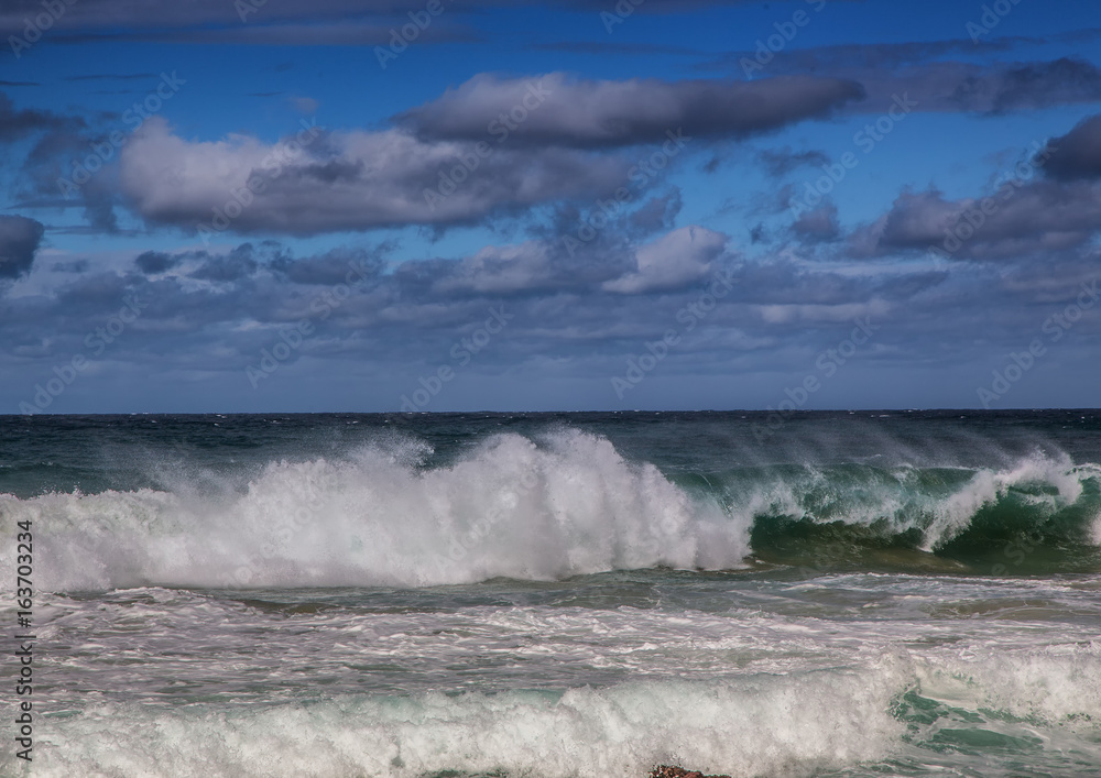 Breaking waves of the Indian Ocean at the Wild Coast of South Africa with cloudy sky