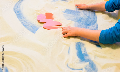 a boy plays with sand in the children's sandbox to develop lessons for toddlers connects fractional parts in a single round