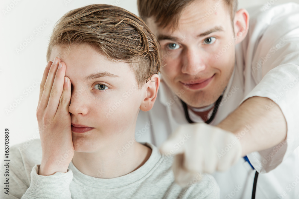 Doctor Standing Behind Teen Boy During Vision Test Doctor Standing Behind Teen Boy During Vision Test