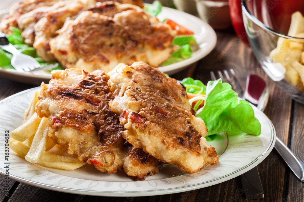Chicken medallions with red peppers served with chips Chicken medallions with red peppers served with chips