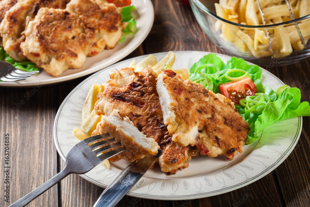 Chicken medallions with red peppers served with chips Chicken medallions with red peppers served with chips
