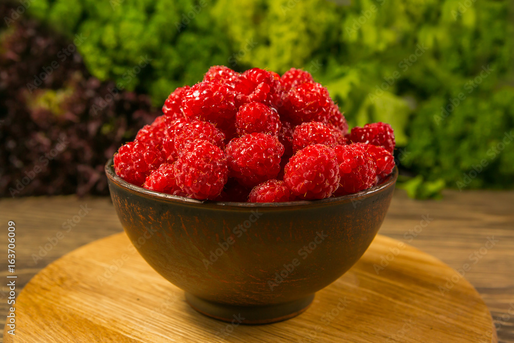 Full bowl of ripe raspberries on a wooden table Full bowl of ripe raspberries on a wooden table
