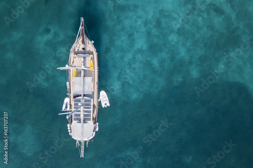 Aerial view of a little yacht on amazing beach with a turquoise and transparent sea. Emerald Coast, Sardinia, Italy. © Travel Wild