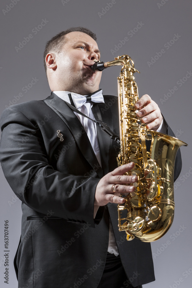 Fototapeta premium Music and Musicians Ideas and Concepts. Portrait of Caucasian Mature Expressive Saxophone Player Playing the Instrument Against White Background.