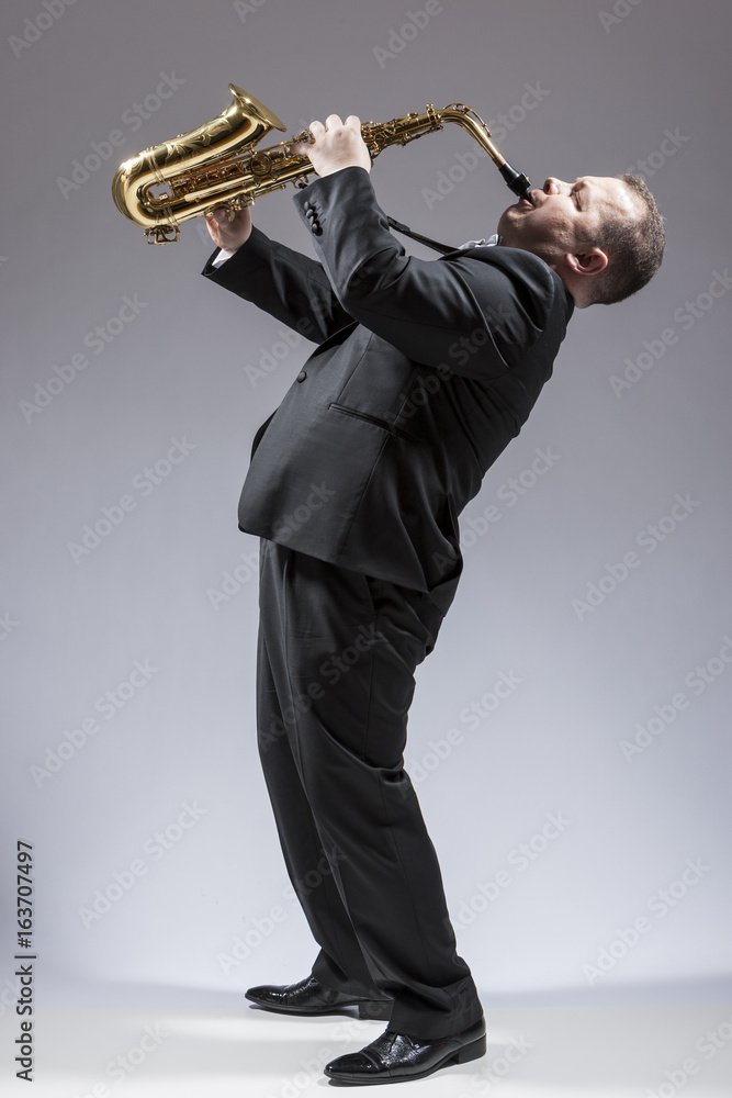 Obraz premium Music and Musicians Ideas and Concepts. Full Length Portrait of Caucasian Mature Expressive Saxophone Player Playing the Instrument Against White