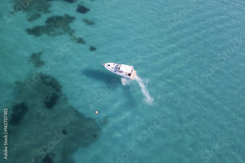 Aerial view of a little yacht on amazing beach with a turquoise and transparent sea. Emerald Coast, Sardinia, Italy.