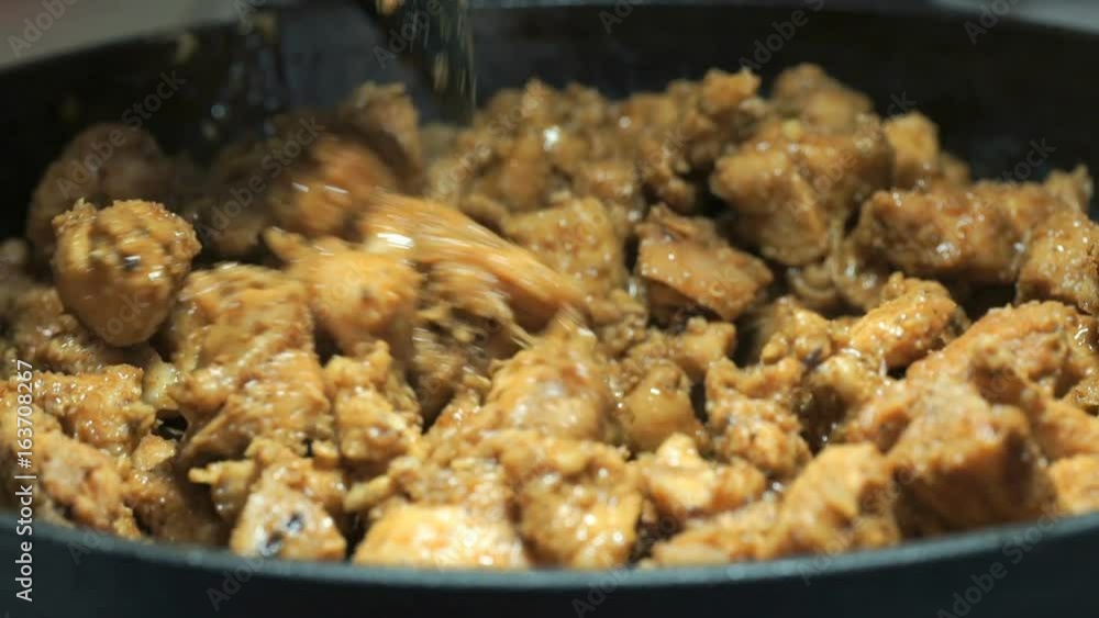 The black plastic spoon mixes fried slices during frying. The process of frying the chopped chicken pieces for cooking kebabs on the cast iron skillet. Close-up The black plastic spoon mixes fried slices during frying. The process of frying the chopped chicken pieces for cooking kebabs on the cast iron skillet. Close-up