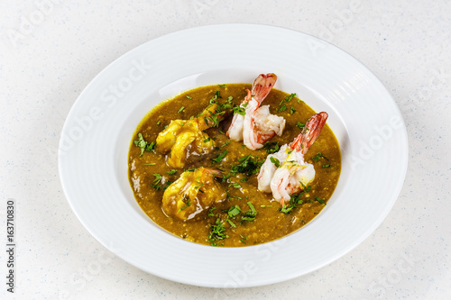 Prawn curry on white plate served with parsley