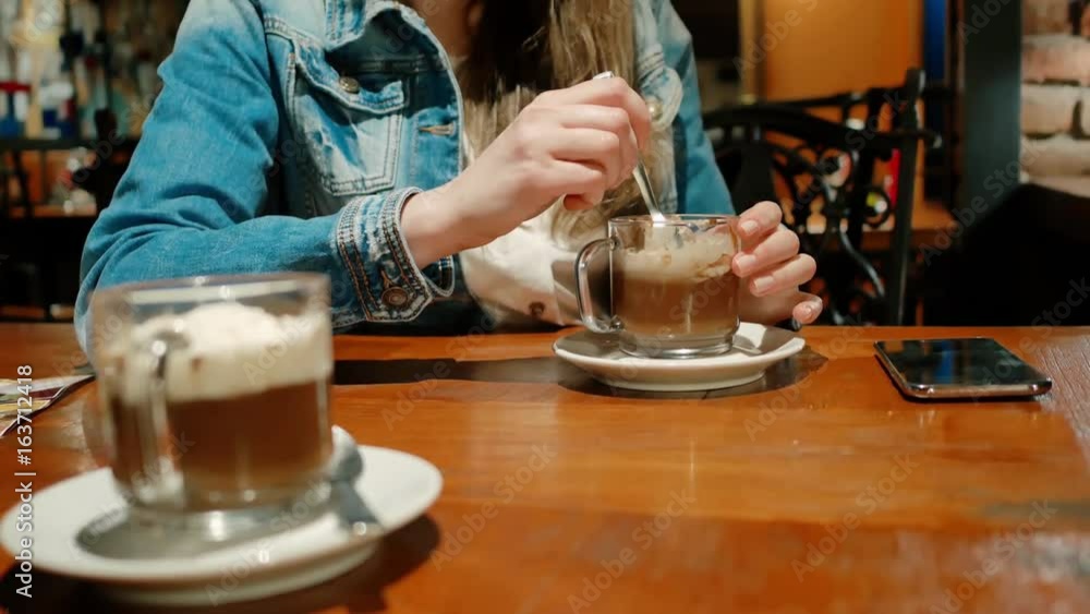 Pretty girl in a cotton jacket with a hot chocolate in a cafe. Vintage interior. Brick wall. Pretty girl in a cotton jacket with a hot chocolate in a cafe. Vintage interior. Brick wall.