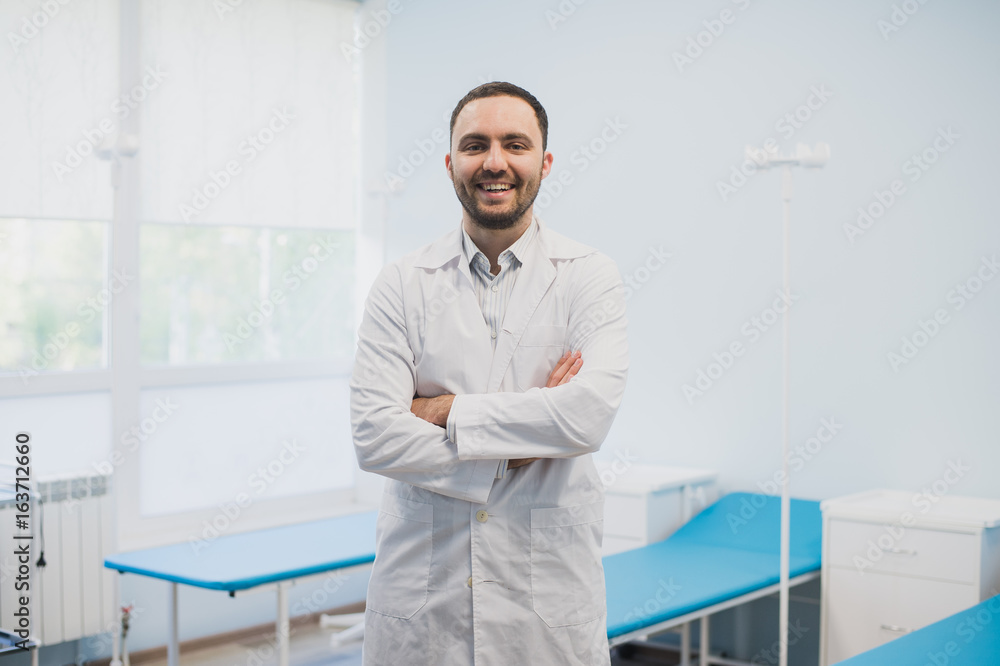 Portrait of a happy male doctor standing with arms crossed at medical office Portrait of a happy male doctor standing with arms crossed at medical office