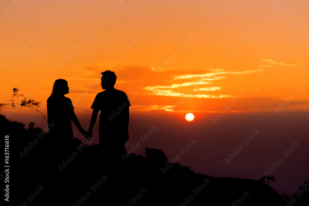 Silouette couple holding hand and look together at sunset.