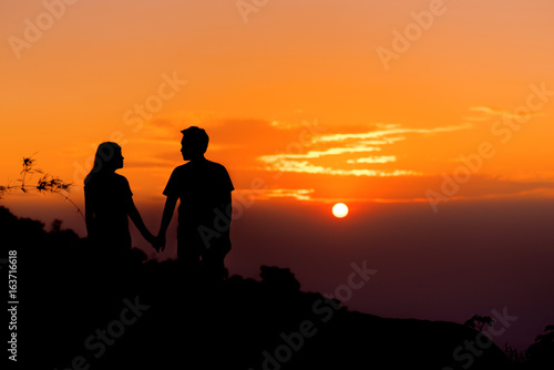 Silouette couple holding hand and look together at sunset.