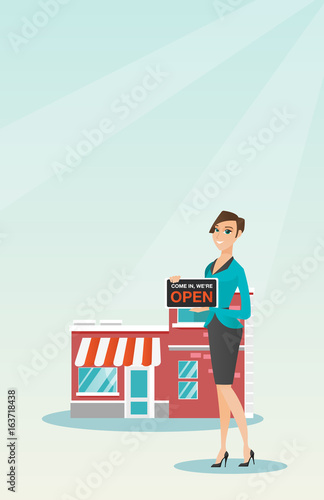 Caucasian shop owner holding open signboard.