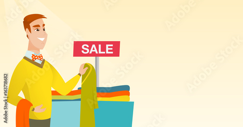 Young man choosing clothes in the shop on sale.