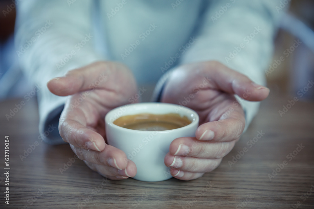 Female hands holding cups of coffee on rustic wooden table background - vintage style effect picture Female hands holding cups of coffee on rustic wooden table background - vintage style effect picture