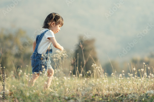 Happy child running outdoors. Little girl playing around the park on beautiful morning. Healthy preschool children summer activity. Kids