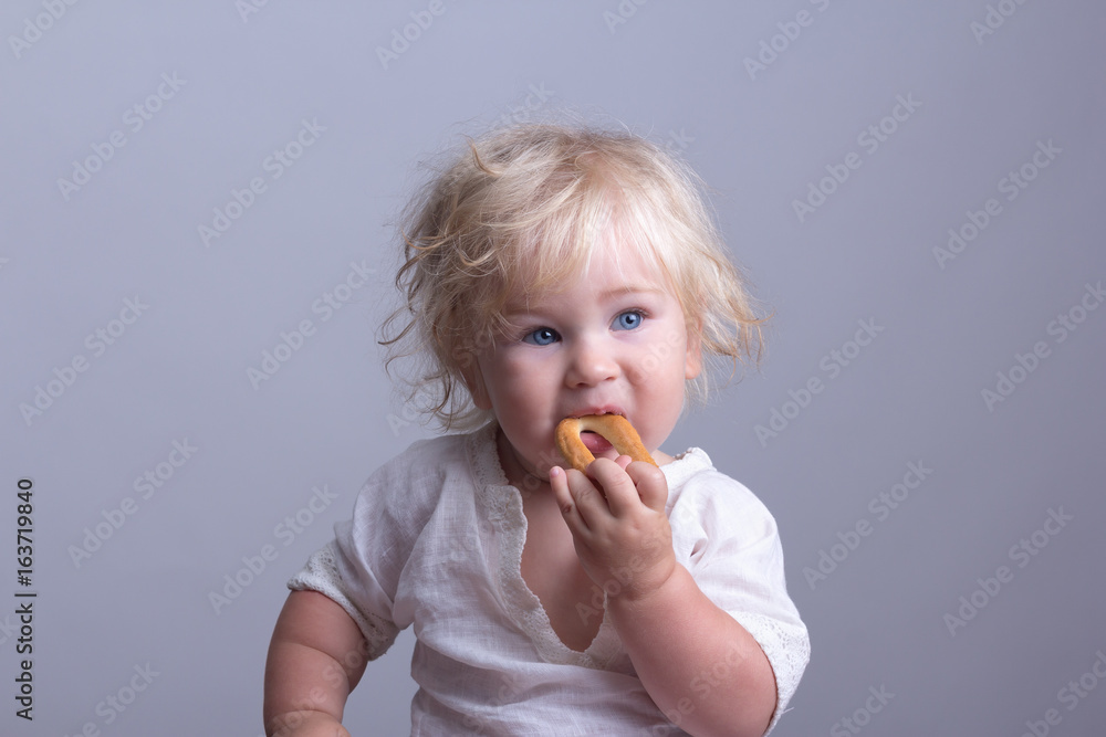 Portrait child blue eyes. The kid eats a bagel. Portrait child blue eyes. The kid eats a bagel.